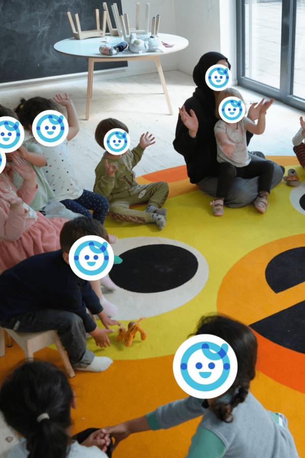 Eine Gruppe Kinder sitzt im Kreis auf dem Boden im Gruppenraum in der Kita kinderzimmer Alsterberg in Hamburg Alsterdorf