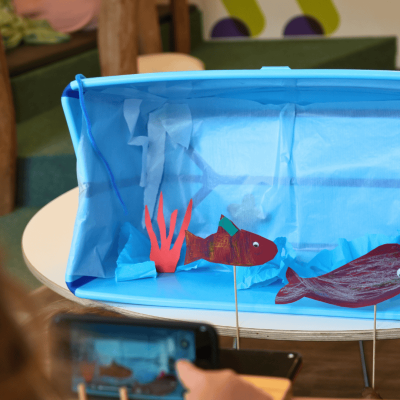 Kinder filmen eine gebastelte Unterwasserwelt für ein Stopmotion Projekt in der Kita kinderzimmer Rodelberg in Hamburg Rahlstedt
