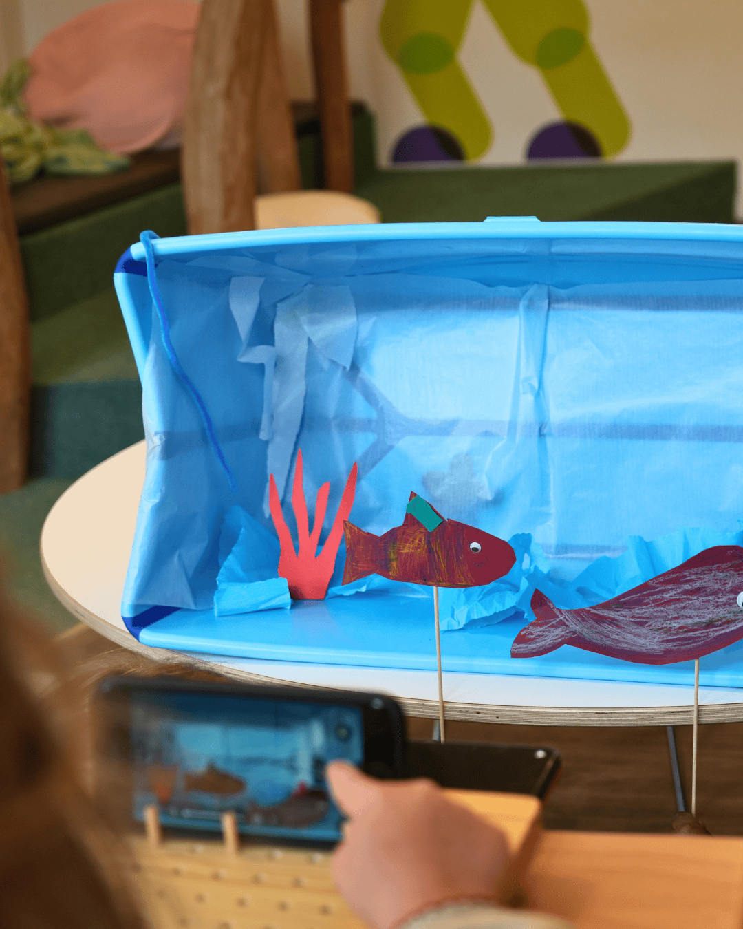 Kinder filmen eine gebastelte Unterwasserwelt für ein Stopmotion Projekt in der Kita kinderzimmer Rodelberg in Hamburg Rahlstedt