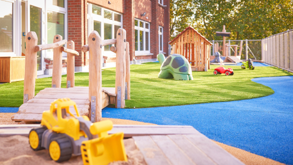 kita-kinderzimmer-hamburg-barmbek-Unnenland_003 Außengelände mit Spielbagger und Holzpfosten auf Kunstrasen – Kita kinderzimmer Unnenland, Hamburg-Barmbek