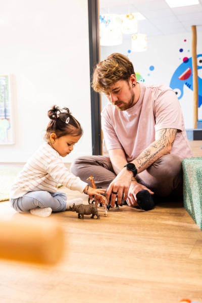 kita-kinderzimmer-hamburg-brand-shooting-kjell-madchen-3x7a3898 Ein Erzieher spielt zusammen mit einem Kind mit Zoofiguren in der Kita kinderzimmer Hamburg