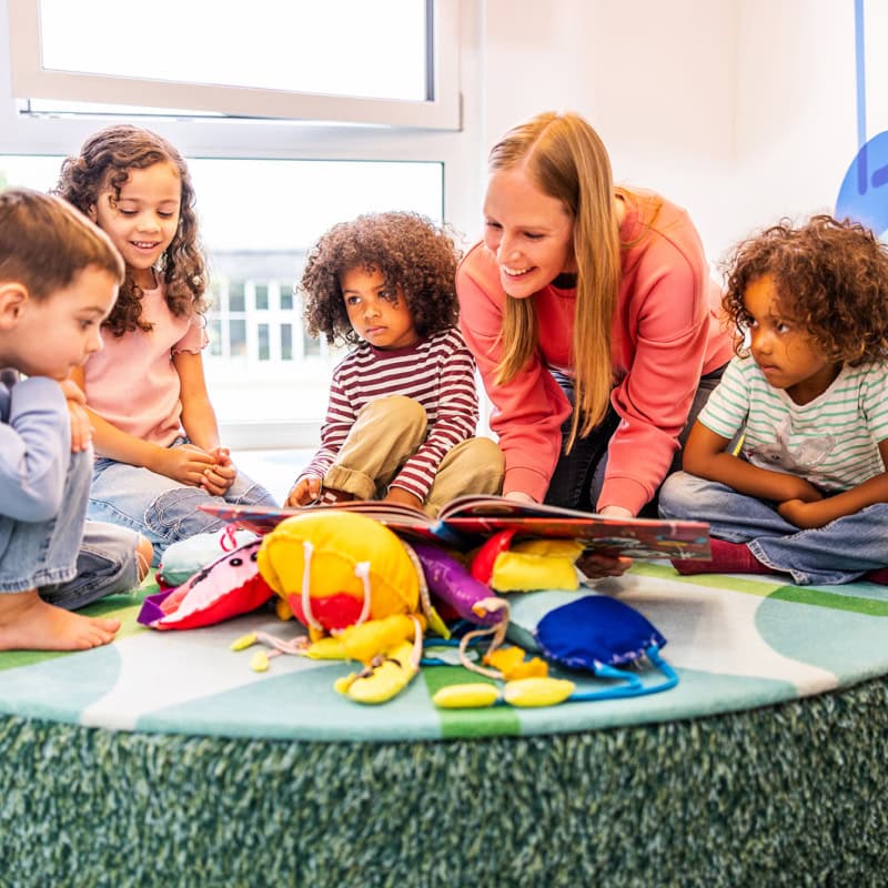 Pädagogin liest 4 Kindern aus Buch vor