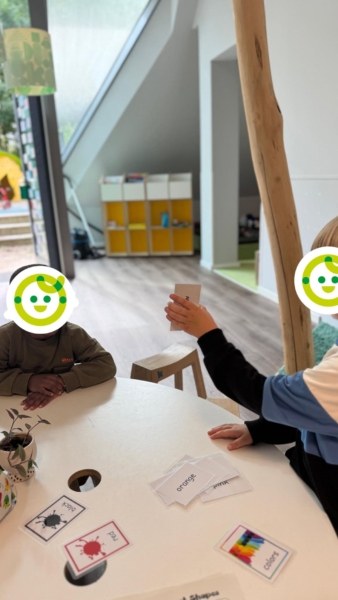 Kinder zeigen sich gegenseitig Karten in der Kita kinderzimmer Inselpark in Hamburg Wilhelmsburg