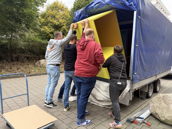 4 Personen verladen Arbeitscubes auf Anhänger vor der Kita kinderzimmer Hamburg