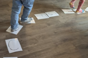 kita-kinderzimmer-heidbrook-hamburg-neugraben-vorschule_6 Buchstaben Legespiel und Kinder laufen drauf in der Vorschule der Kita kinderimmer Heidbrook Hamburg Neugraben Fischbek
