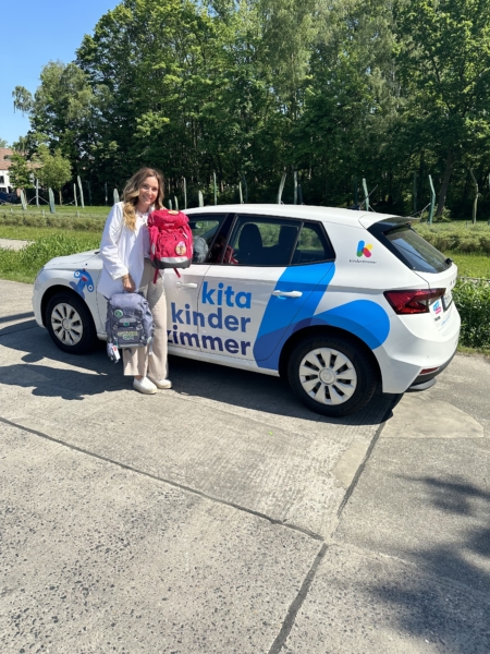 Kita-Leitung Deborah präsentiert zwei gespende Schulranzen vor ihrem Auto in der Kita kinderzimmer Heidbrook in Hamburg Rahlstedt